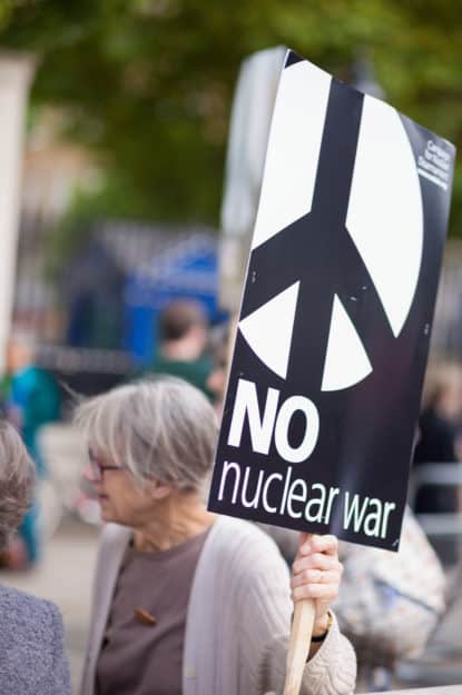 woman holding a "no to nuclear war" placard