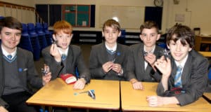 Five students hold up paper cranes they have made during a CND Peace Education workshop.