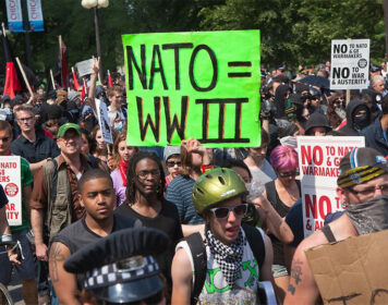 Anti-NATO protest with placrd reading "NATO = WWIII"