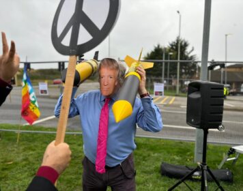 Protester at RAF Laknheath wears Donald Trump mask and holds two cardboard nuclear missiles